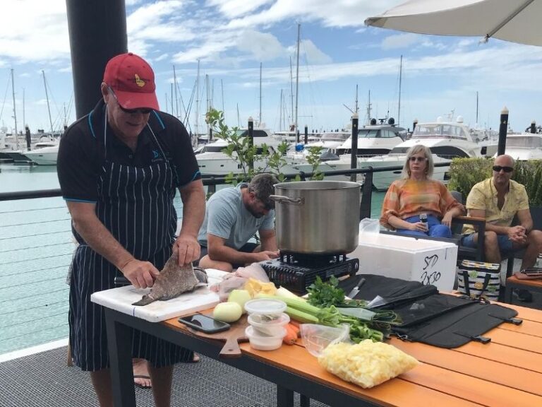 A chef doing a cooking demonstration at a marina with locally caught fish and fresh vegetables