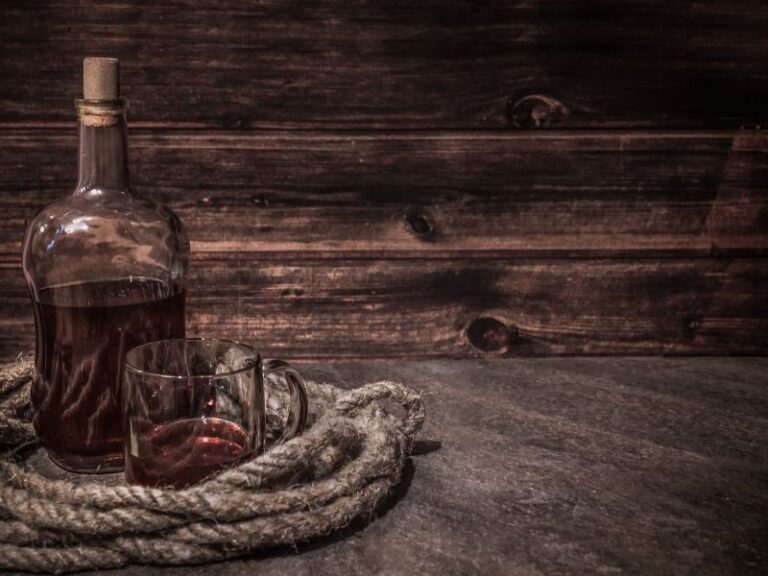 A bottle of rum with vessel rope on a wooden table